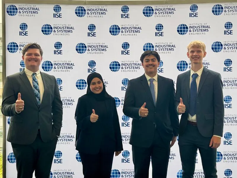 The four-person team in front of an IISE step-and-repeat banner at the 2026 IISE Annual Conference.